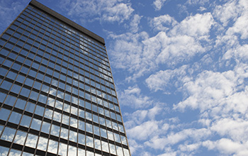 tall building with glass exterior against a blue sky with sparse clouds