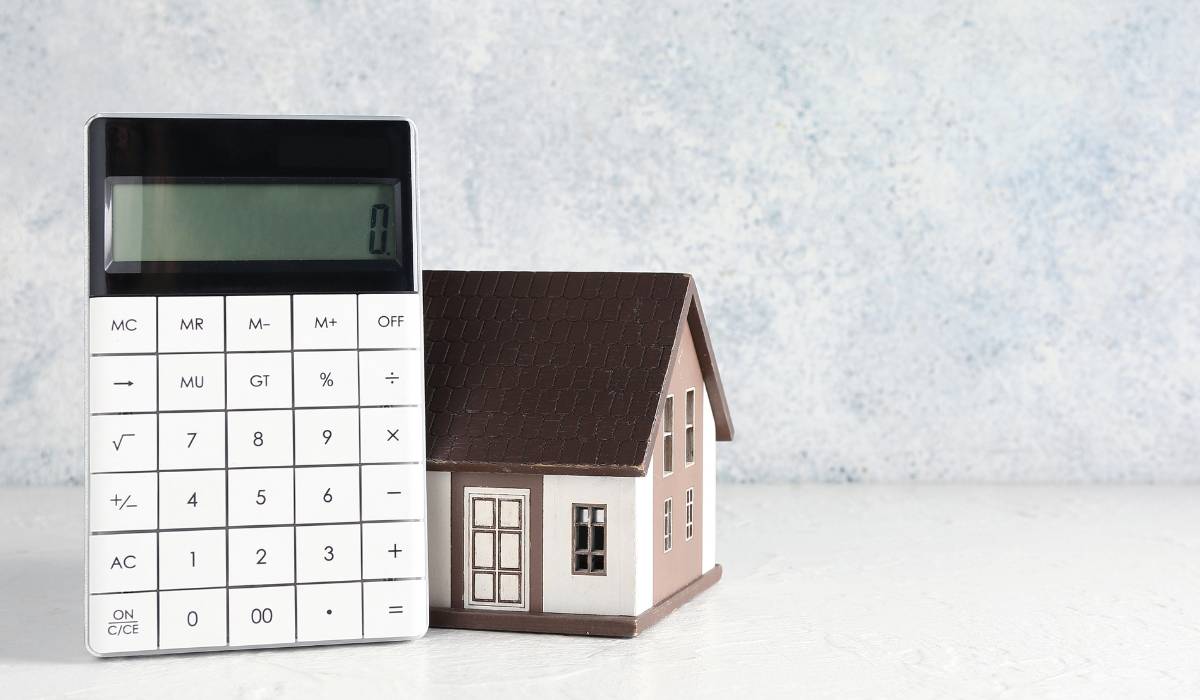 Calculator and house model in front of a wall
