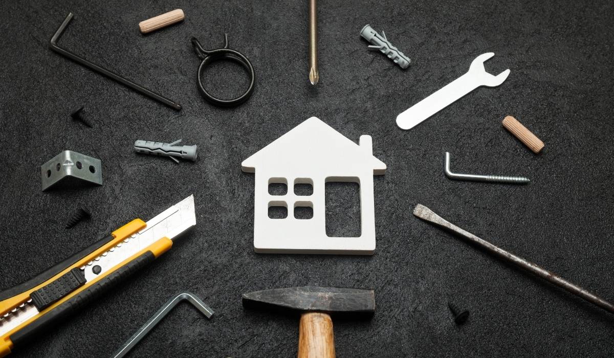 Tools used in the construction of a house on a black background with house in middle