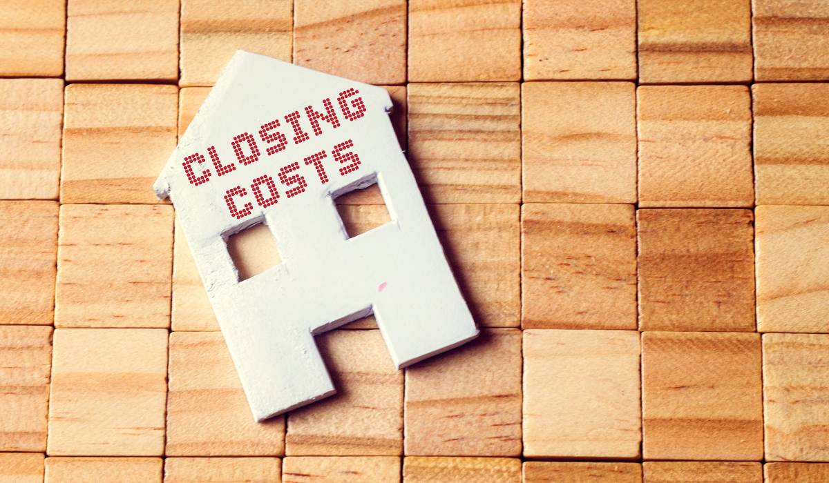 Closing costs written on a cut out of a house with wooden blocks on the background to show a pre-construction condo.