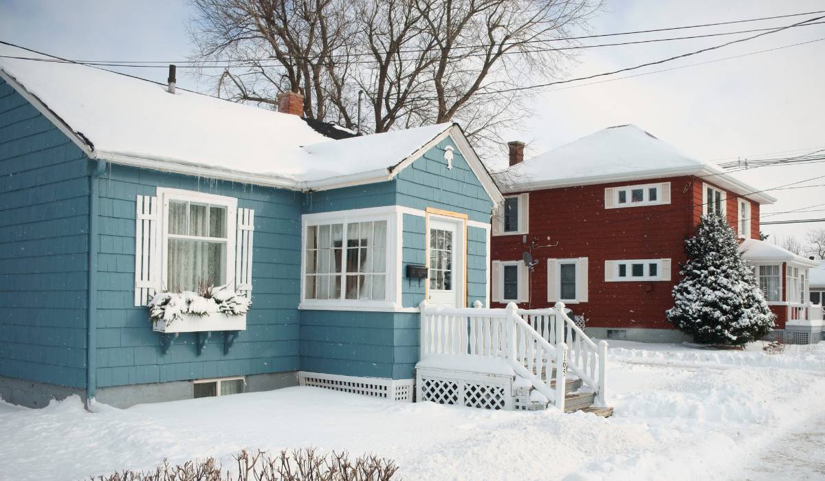 A cyan blue and a red house side by side covered in snow.