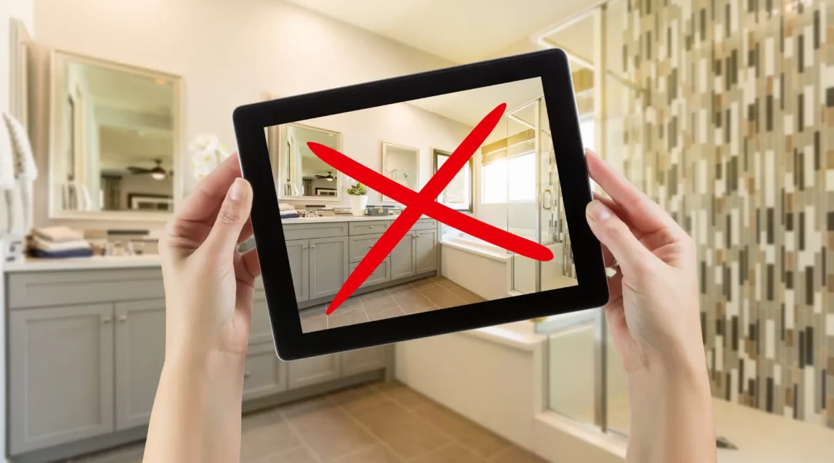 a person holding up a tablet in front of a bathroom with a cross sign on it